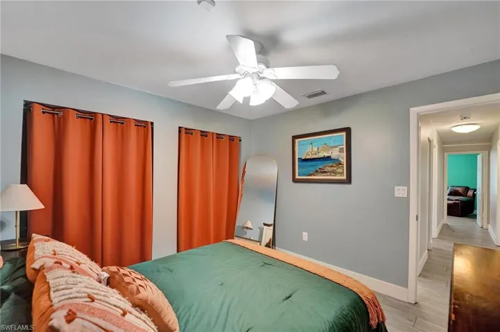 Bedroom featuring light wood finished floors, baseboards, and a ceiling fan