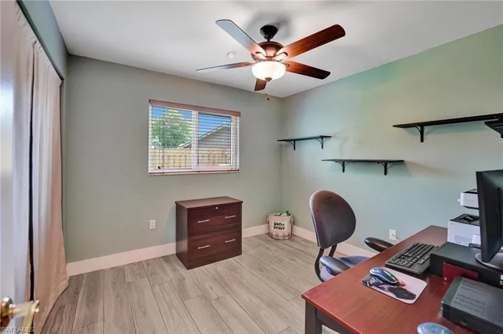 Office space featuring a ceiling fan, baseboards, and light wood-type flooring