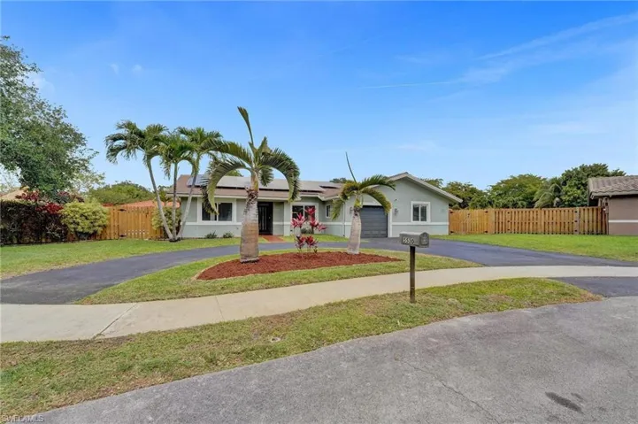 Single story home featuring driveway, solar panels, a garage, and stucco siding