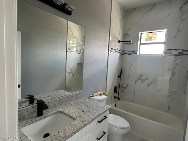 Full bathroom featuring vanity, toilet, and tiled shower / bath combo