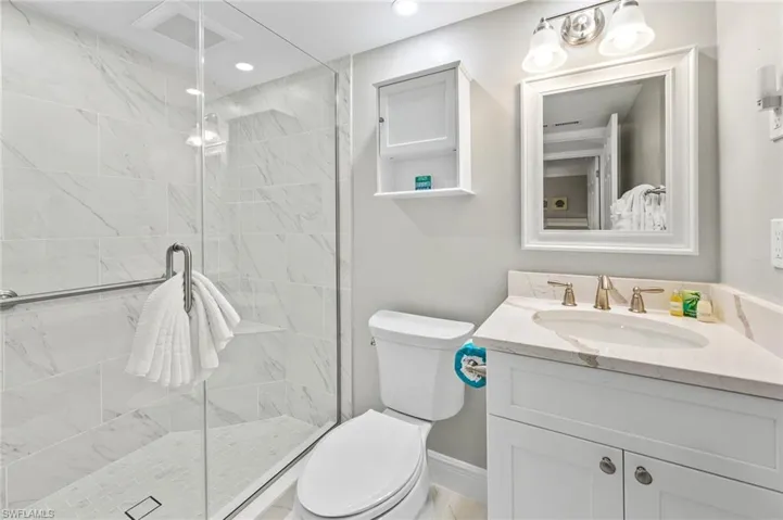 Full bath featuring vanity, a marble finish shower, and recessed lighting
