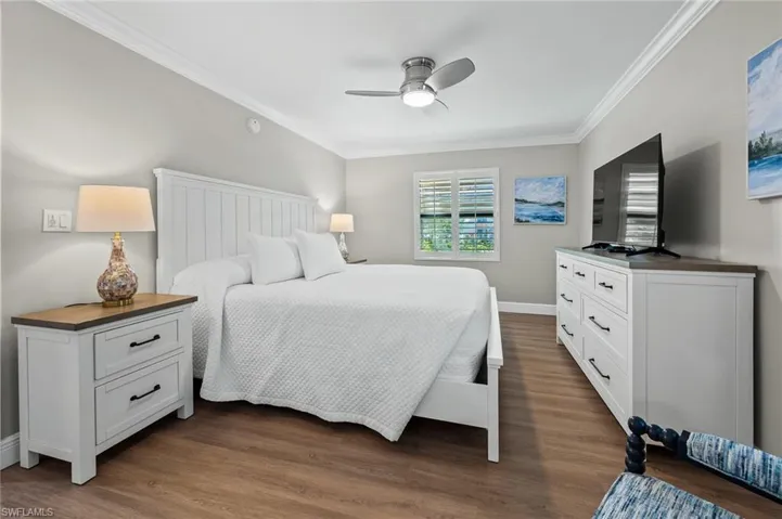 Bedroom featuring dark wood-type flooring, ornamental molding, and a ceiling fan