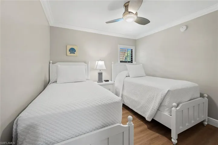 Bedroom featuring wood finished floors, crown molding, and ceiling fan
