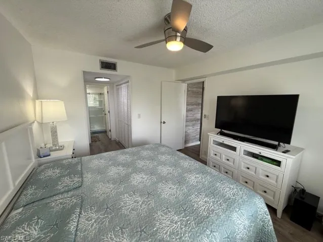 Bedroom featuring ceiling fan, dark wood-style flooring, and a textured ceiling