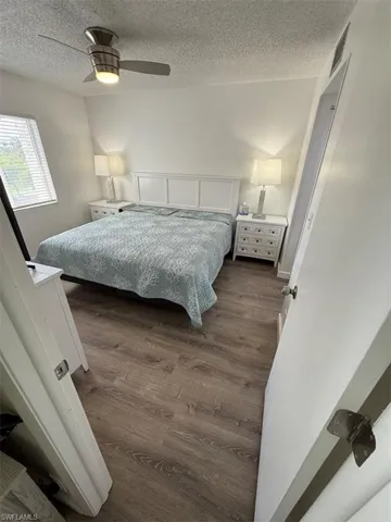 Bedroom with dark wood finished floors, ceiling fan, and a textured ceiling