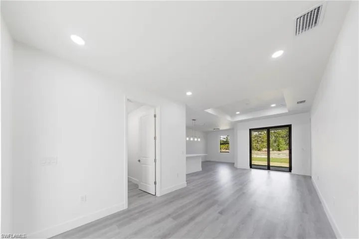 Unfurnished living room featuring a tray ceiling, recessed lighting, and light wood finished floors