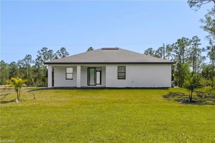 Rear view of house featuring a lawn and stucco siding