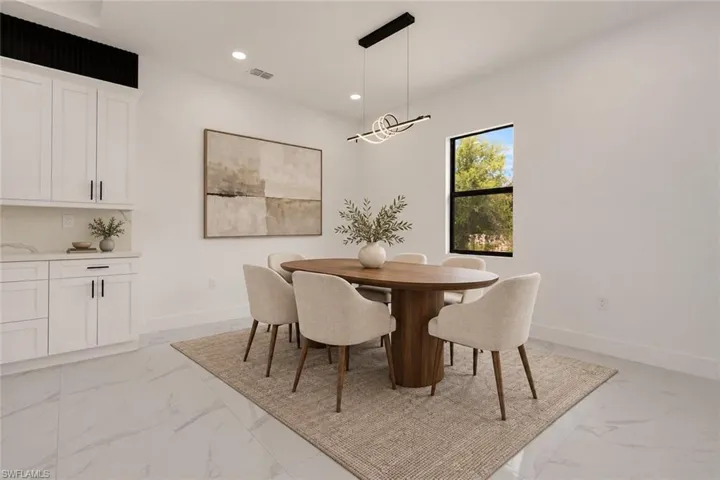 White shaker cabinetry, recessed lighting, and a modern linear chandelier illuminate this space
