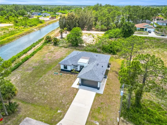 Contemporary residence with a dark shingle roof, attached garage, and a long concrete driveway