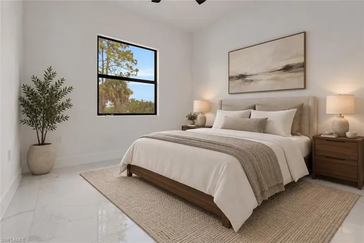 Vaulted ceiling, white walls, large window with black trim, light-toned tile flooring, and a ceiling fan