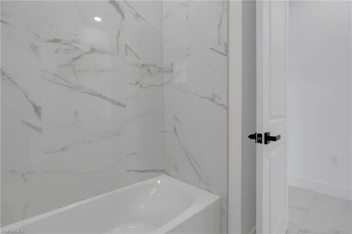 White soaking tub with large format marble-look tile surround