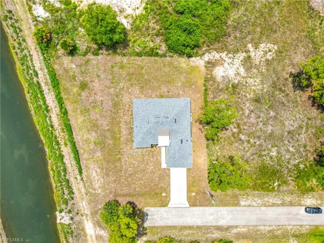Aerial view showcasing a detached single-story residence with a gray shingle roof