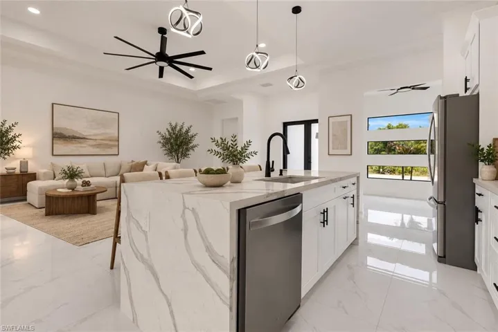 Gourmet kitchen with a waterfall countertop island, stainless steel appliances, and white shaker cabinetry