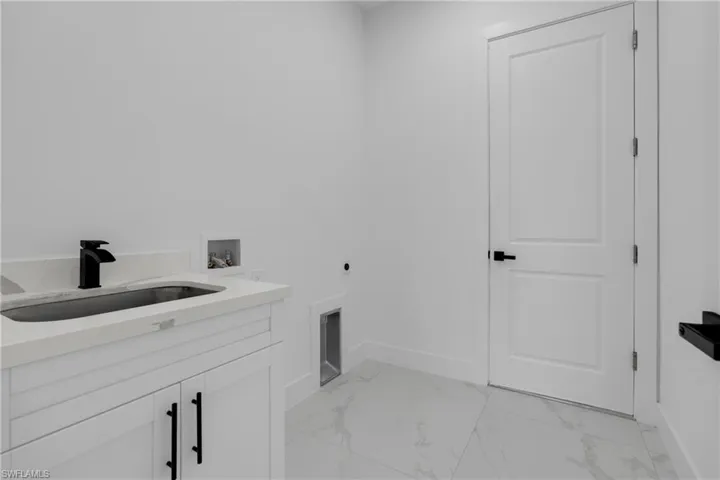 Laundry area featuring white cabinetry, a rectangular undermount sink, a matte black faucet, and white countertop