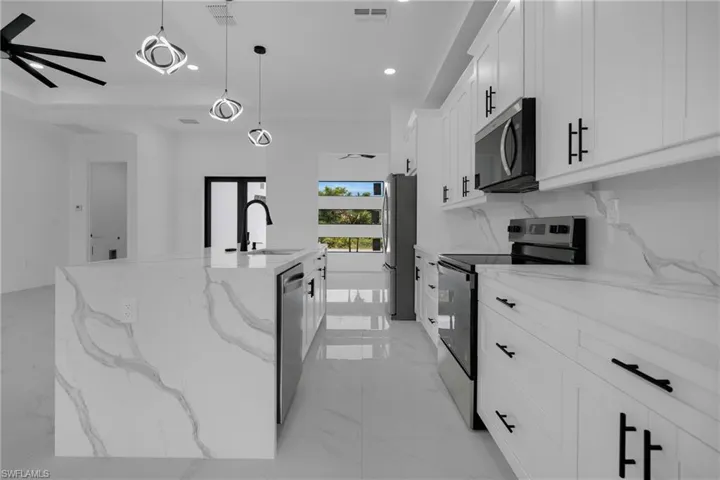 Kitchen featuring a waterfall-edge island, integrated sink with matte black faucet, and stainless steel appliances