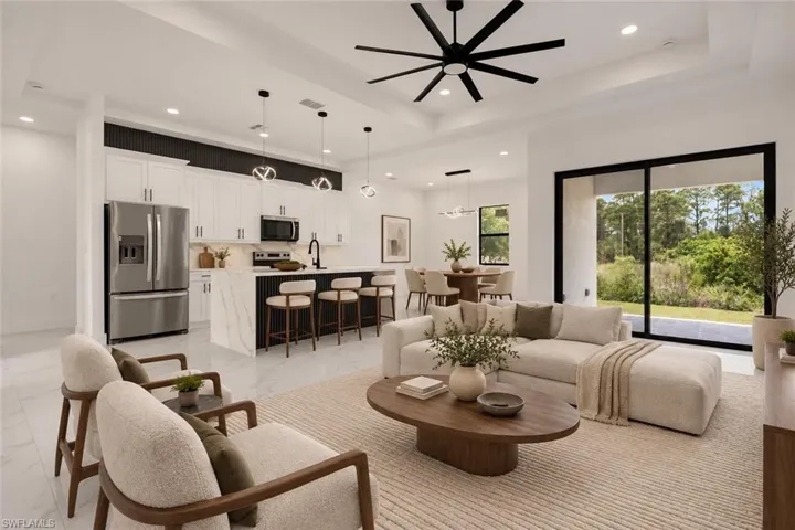 Open-concept living space featuring a modern kitchen with a waterfall island, white cabinetry, and stainless steel appliances