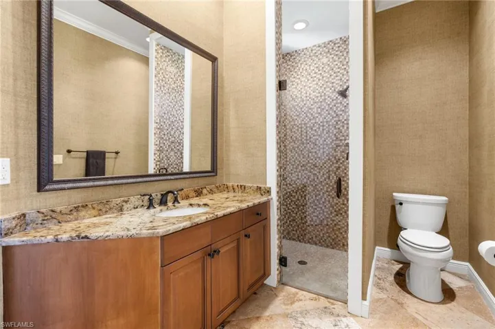 Bathroom featuring toilet, ornamental molding, walk in shower, and vanity