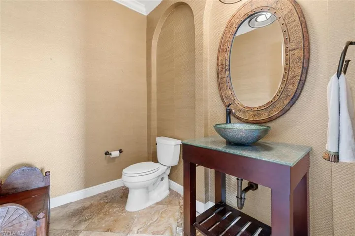 Bathroom with toilet, crown molding, and sink