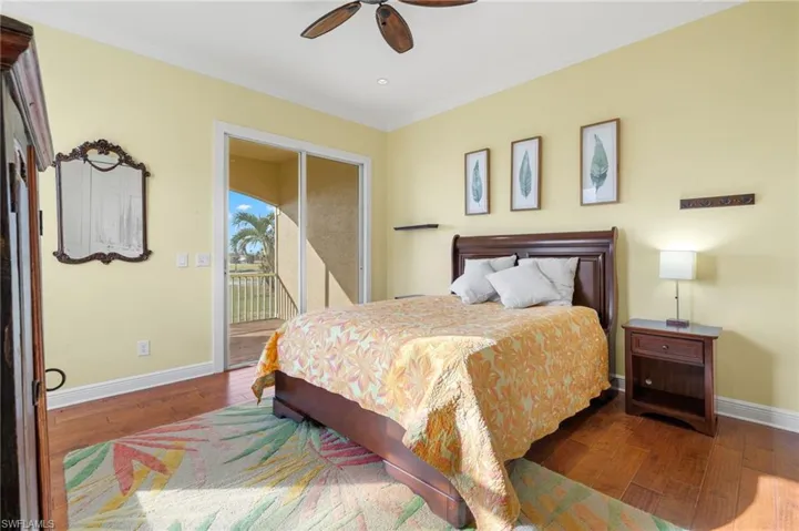 Bedroom with ceiling fan, ornamental molding, dark hardwood / wood-style flooring, and access to exterior