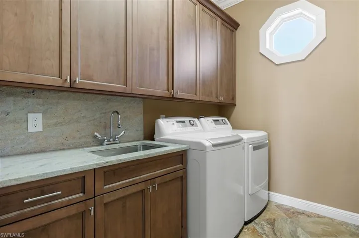 Washroom with cabinets, crown molding, washer and dryer, and sink