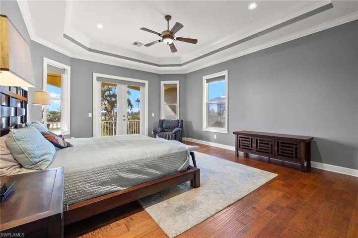 Bedroom featuring access to outside, a raised ceiling, ceiling fan, dark wood-type flooring, and crown molding