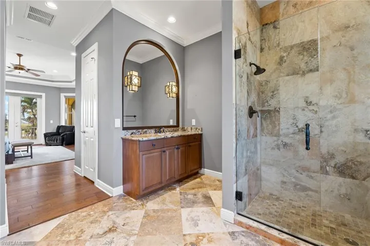 Bathroom with hardwood / wood-style flooring, a shower with shower door, crown molding, vanity, and ceiling fan