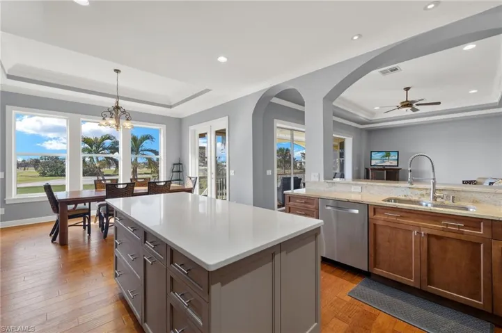 Kitchen with a tray ceiling, sink, a kitchen island, and dishwasher
