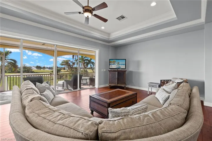 Living room featuring crown molding, ceiling fan, a tray ceiling, and dark hardwood / wood-style flooring