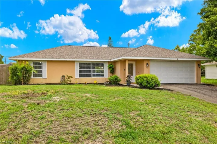 Single story home with a garage and a front yard