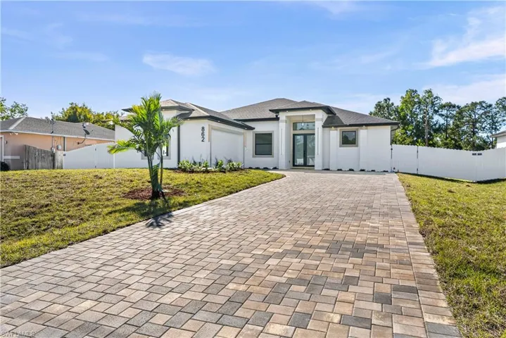 View of front of home with decorative driveway, an attached garage, stucco siding, and french doors