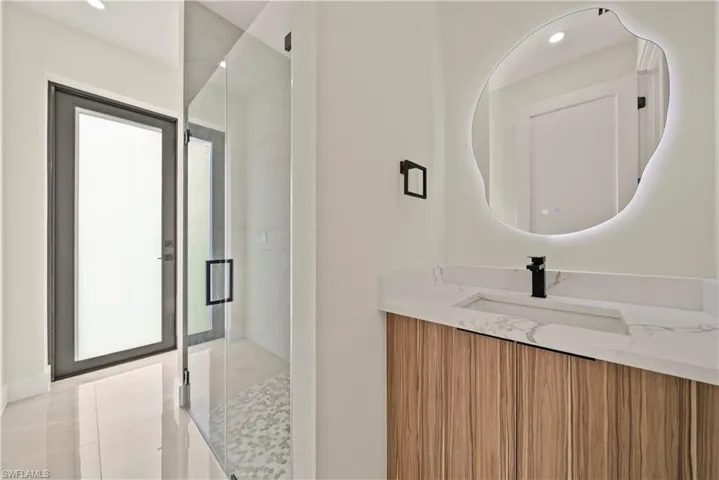 Full bath with vanity, a marble finish shower, and recessed lighting