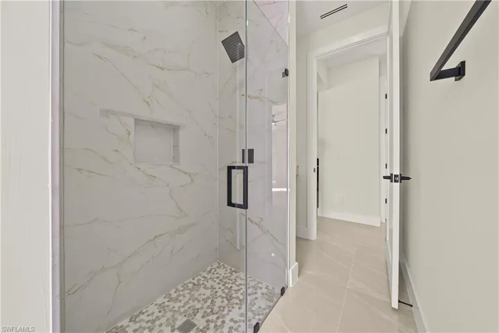 Bathroom with a marble finish shower and baseboards