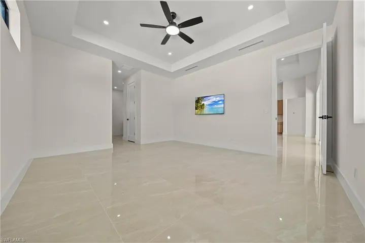 Unfurnished room featuring a raised ceiling, recessed lighting, ceiling fan, and light marble finish floors