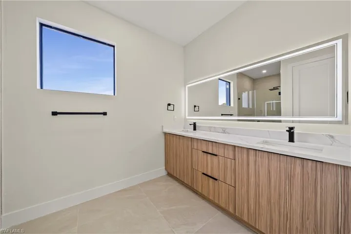 Full bathroom with a shower stall, double vanity, and plenty of natural light