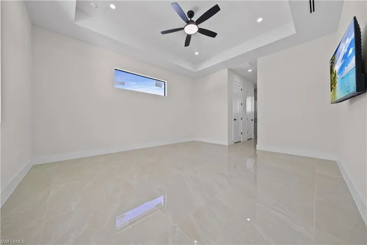 Unfurnished room featuring a raised ceiling, ceiling fan, and recessed lighting