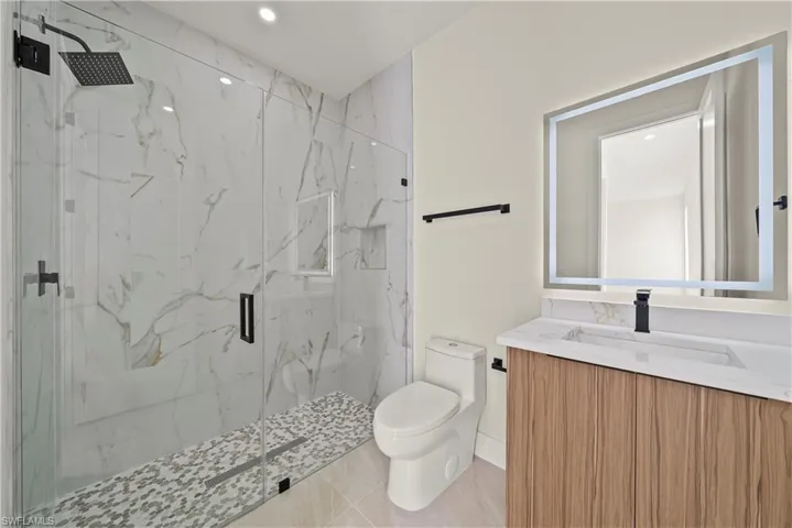 Bathroom with vanity, a marble finish shower, recessed lighting, and light tile patterned flooring