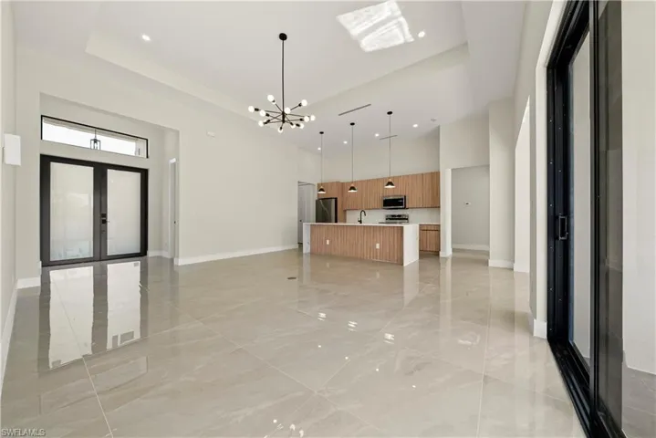 Kitchen with open floor plan, a spacious island, a tray ceiling, hanging lights, and stainless steel appliances