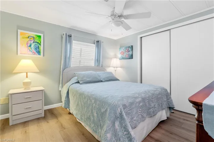Bedroom with ornamental molding, light wood-type flooring, ceiling fan, and a closet