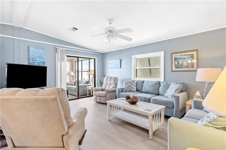 Living room with ceiling fan, wood finished floors, lofted ceiling, and ornamental molding