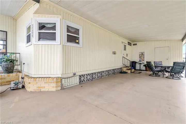 View of side of property featuring outdoor dining space, entry steps, and a patio
