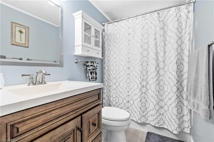 Full bath with vanity, shower / tub combo with curtain, and ornamental molding