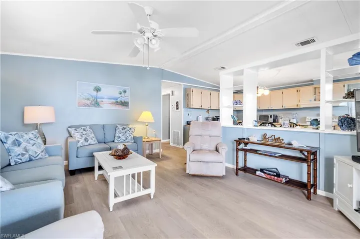 Living area with a ceiling fan, light wood-style flooring, and lofted ceiling