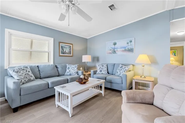 Living area featuring ornamental molding, wood finished floors, ceiling fan, and lofted ceiling