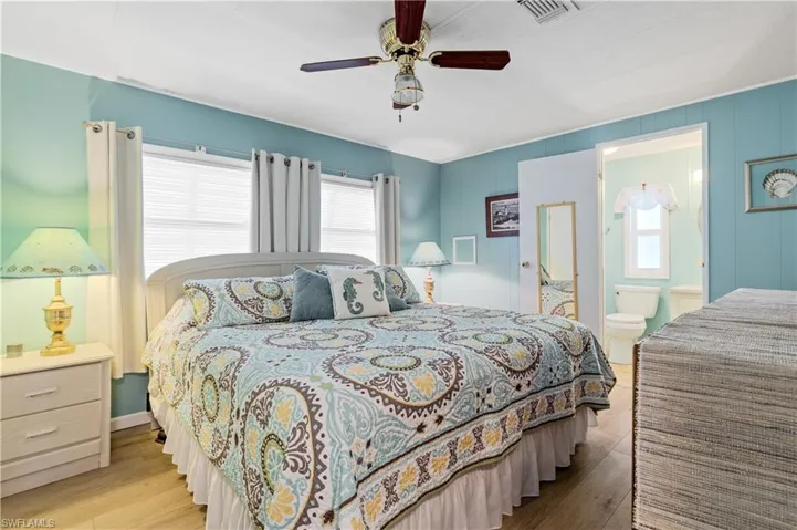 Bedroom featuring wood finished floors, ceiling fan, and ensuite bathroom