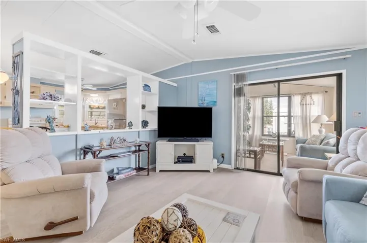 Living area with a ceiling fan, wood finished floors, and lofted ceiling