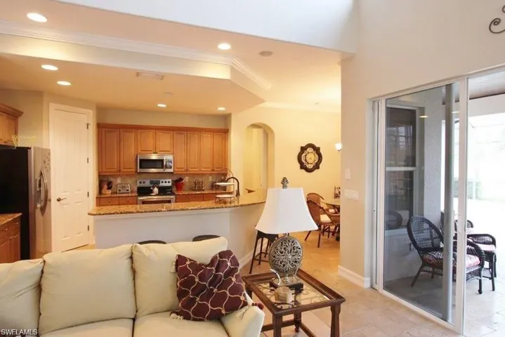 Kitchen with light stone countertops, appliances with stainless steel finishes, recessed lighting, crown molding, and open floor plan