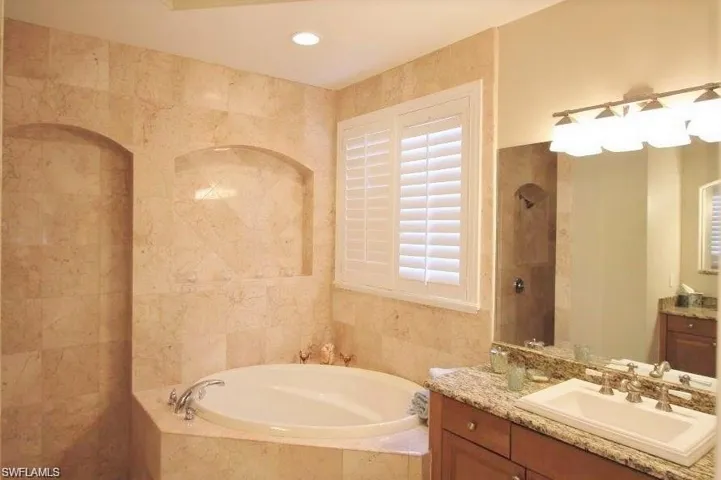Full bathroom featuring vanity, a garden tub, tile walls, a tile shower, and recessed lighting