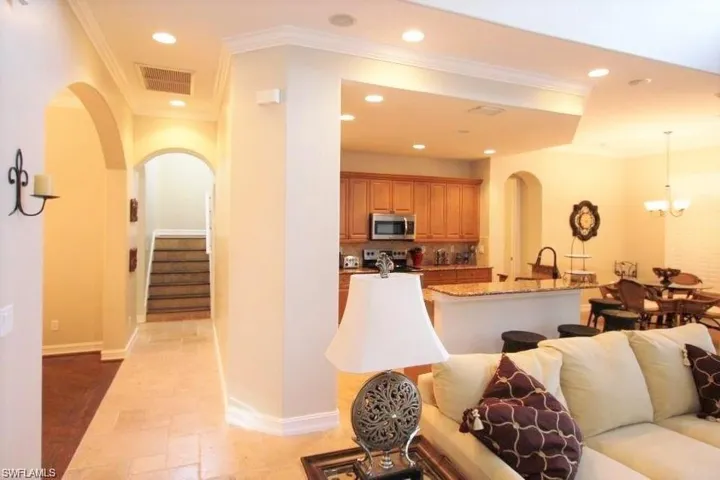 Living room featuring arched walkways, crown molding, recessed lighting, stairway, and a chandelier