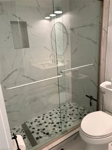 Full bathroom featuring a marble finish shower and toilet