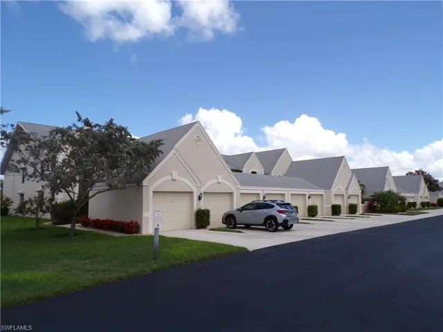 View of front of house with stucco siding, a front lawn, and driveway
